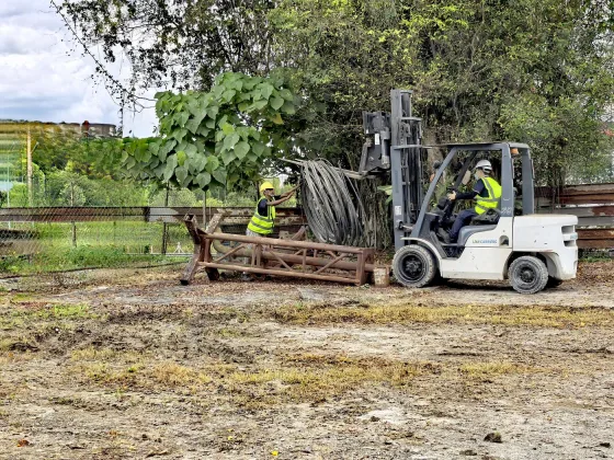 XXL Space Share forklift lifting a steel truss while a worker guides it